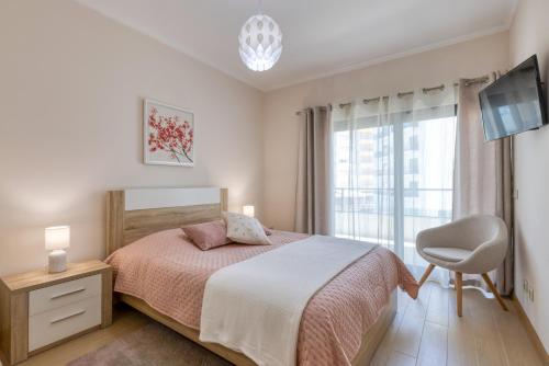 um quarto com uma cama, uma cadeira e uma janela em Rocha Prime Luxury Apartment em Portimão