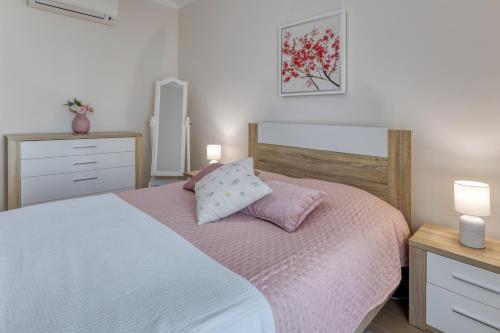 um quarto com uma cama com lençóis cor-de-rosa e 2 candeeiros em Rocha Prime Luxury Apartment em Portimão