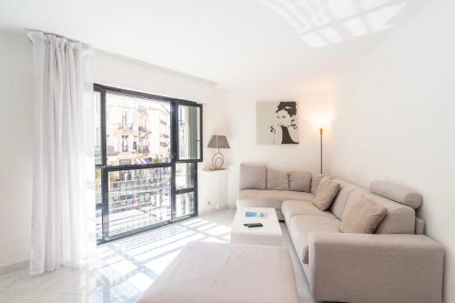 un salon avec un canapé et une grande fenêtre dans l'établissement Cannes Rue d'Antibes Premium 2 BDR 2 baths Exclusive Olam Properties, à Cannes