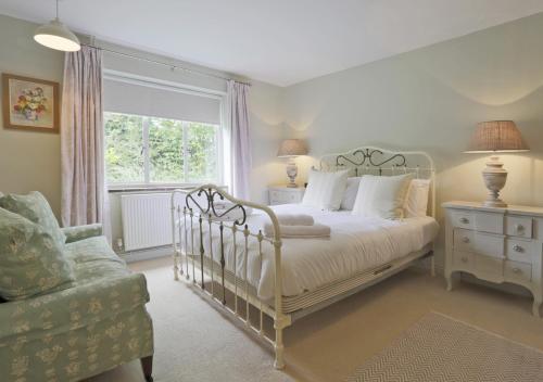 a bedroom with a bed and a chair and a window at Little Meadow in Walberswick