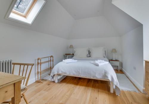 a white bedroom with a bed and a window at Lodge Farm Barn in Sudbourne