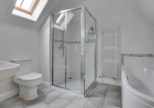 a bathroom with a shower and a toilet and a sink at Lodge Farm Barn in Sudbourne