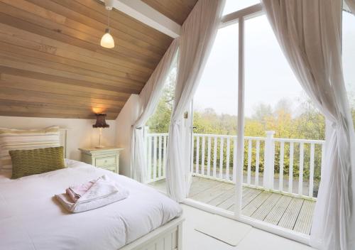 a bedroom with a bed and a large window at Meadow Lodge in Ufford