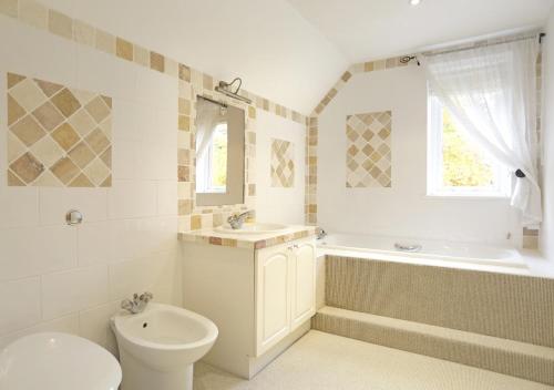 a bathroom with a toilet and a tub and a sink at Meadow Lodge in Ufford