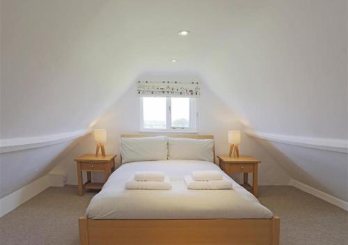 a white bedroom with a bed with two night stands at Kings Farm in Wangford