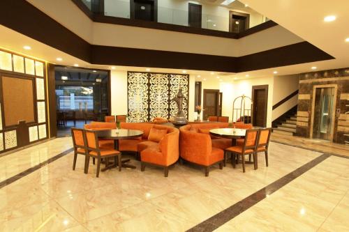 a lobby with orange chairs and a dining room at Lemon Tree Hotel, Katra in Katra