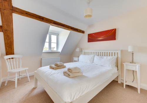 a bedroom with a white bed with towels on it at Meadow House in Blythburgh