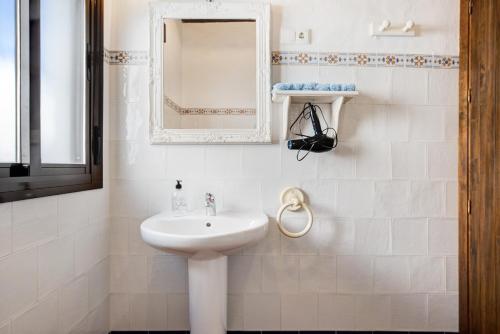 biała łazienka z umywalką i lustrem w obiekcie Apartamento Clara 1 w mieście Conil de la Frontera