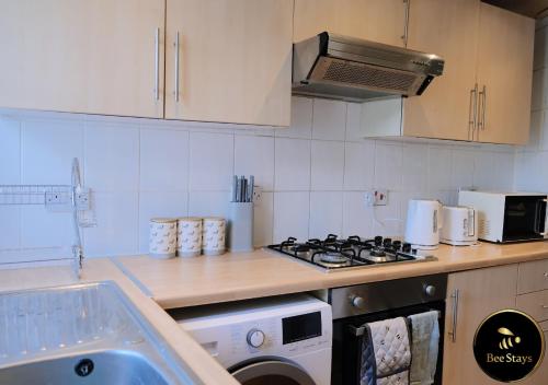 a kitchen with a stove and a washing machine at Bee Stays - Cooper House in Haydock