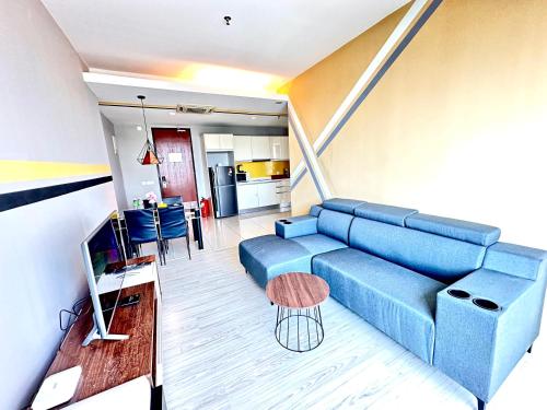 a living room with a blue couch and a table at Cozy Living Sky Apartment in Kota Kinabalu