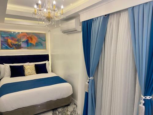a bedroom with a bed with blue curtains and a chandelier at MAKATI Isabela Luxury in Manila