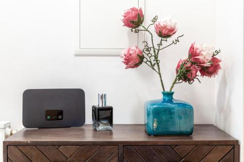 a blue vase with pink flowers on a wooden cabinet at nidusROOMS: Art Déco Apartment nähe Heidelberg in Leimen