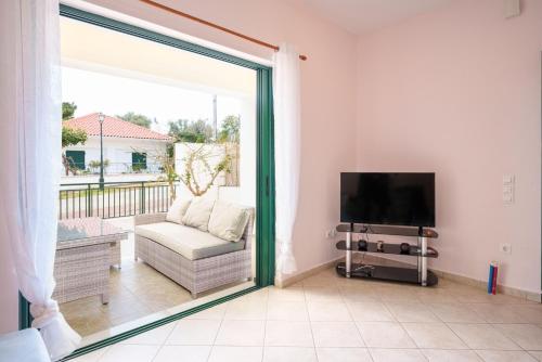 a living room with a sliding glass door and a television at Niko's Central Skala Apartments in Skala Kefalonias