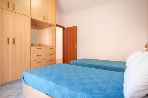 a bedroom with two beds with blue sheets and wooden cabinets at Niko's Central Skala Apartments in Skala Kefalonias