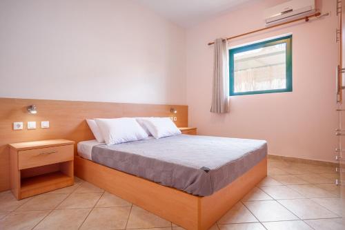 a bedroom with a bed and a window at Niko's Central Skala Apartments in Skala Kefalonias