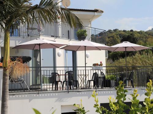 a balcony with tables and chairs and umbrellas at Assabinirica in Acquedolci