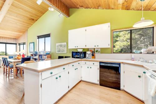a kitchen with white cabinets and a green wall at Sea View in Sea Ranch