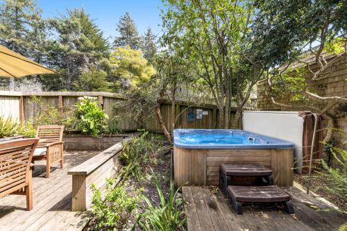 a hot tub in a backyard with a table and benches at Sea View in Sea Ranch