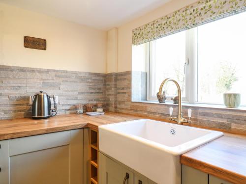 a kitchen with a white sink and a window at Tolldish Cottage in Stafford