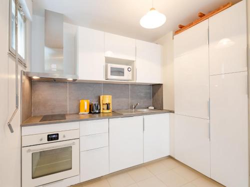 kuchnia z białymi szafkami i kuchenką mikrofalową w obiekcie Apartment Le Grand Large-1 by Interhome w miejscowości Sainte-Maxime