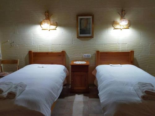 a room with two beds and two lights on the wall at Gozo Rustic Farmhouse with stunning views and swimming pool in Sannat