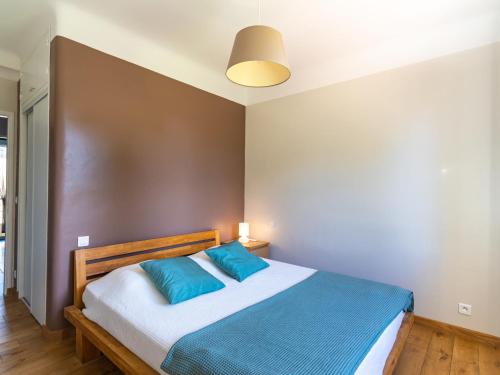 una camera con un letto con due cuscini blu di Apartment Boutin by Interhome a Le Lavandou