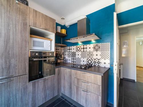 - une cuisine avec des murs bleus et des placards en bois dans l'établissement Apartment Boutin by Interhome, au Lavandou