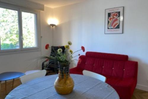 un salon avec une table et un canapé rouge dans l'établissement Lumineux 70m cosy à proximité de la plage, à Arcachon