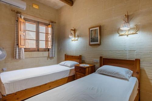 una camera con due letti e una finestra di Gozo Rustic Farmhouse with stunning views and swimming pool a Sannat