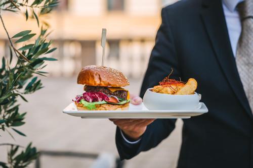a man in a suit holding a plate with a sandwich at Esplanade Zagreb Hotel in Zagreb