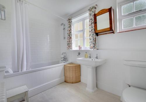 baño blanco con lavabo, bañera y aseo en Mill Cottage en Ufford