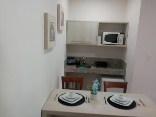 a kitchen with a table with plates and a microwave at Loft Porto Marina Itacuruçá in Mangaratiba