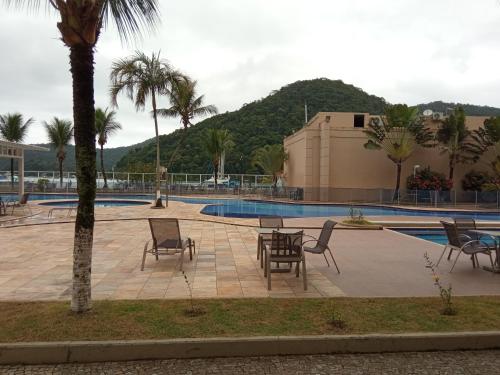 un patio con mesas y sillas junto a una piscina en Loft Porto Marina Itacuruçá en Mangaratiba