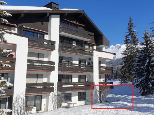 a building with a red object in front of it in the snow at Apartment Uehlinger Seegarten Wirz by Interhome in Lenzerheide