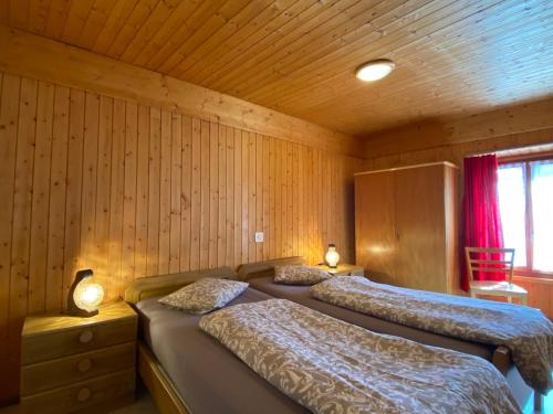 Duas camas num quarto com paredes de madeira em Apartment Casa della Posta-2 by Interhome em Rossa