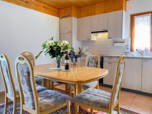 a kitchen with a table and chairs with a bottle of wine at Apartment Della Posta Cervo Giardino by Interhome in Rossa