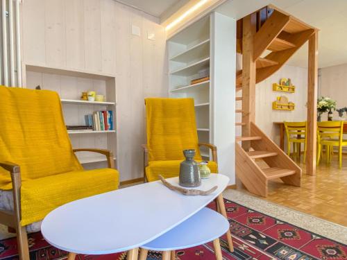 ein Wohnzimmer mit gelben Stühlen und einem weißen Tisch in der Unterkunft Apartment Casa della Posta-1 by Interhome in Rossa