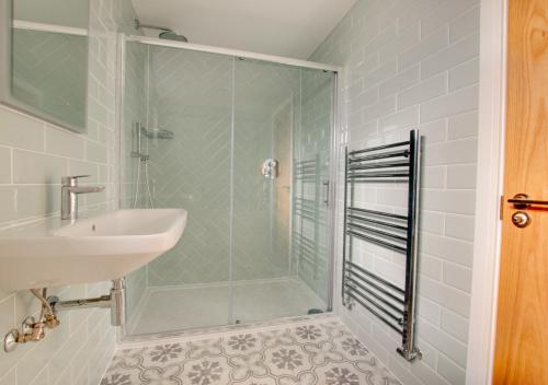 uma casa de banho com uma cabina de duche em vidro e um lavatório. em North South em Southwold
