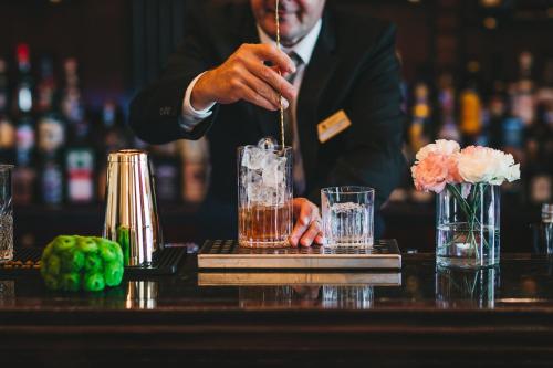 a bartender making a drink at a bar at Esplanade Zagreb Hotel in Zagreb