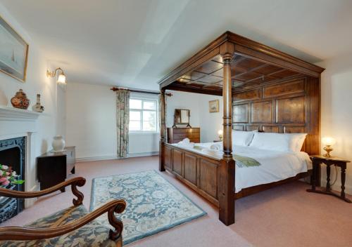 a bedroom with a large canopy bed and a fireplace at Old Brewery House in Orford