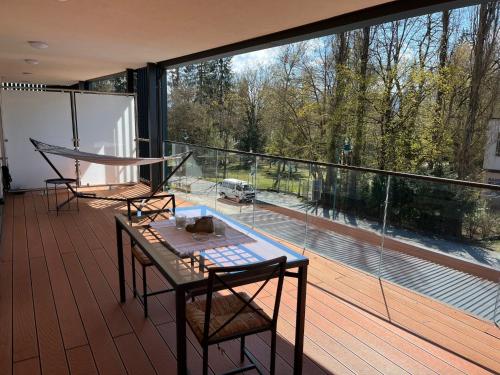 d'un balcon avec une table, des chaises et une grande fenêtre. dans l'établissement Apartment Luxury Sunrise Appartement by Interhome, à Pörtschach am Wörthersee