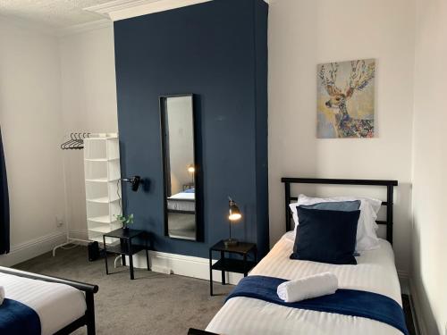 a bedroom with blue walls and a bed with a mirror at Rawling - Welcoming 3 bed apartment with free Wifi and Free Parking in Gateshead