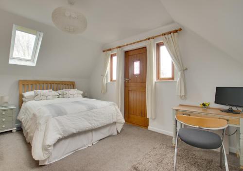 a bedroom with a bed and a desk and a television at Owl Lodge in Ufford