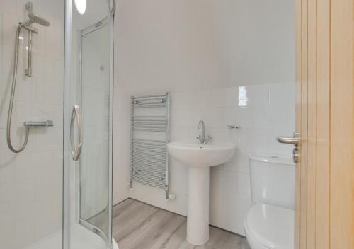 a white bathroom with a sink and a shower at Owl Lodge in Ufford