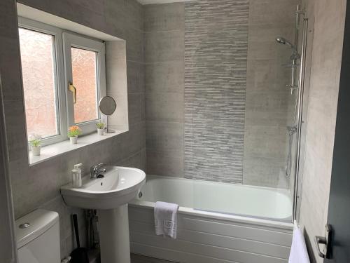 y baño con bañera, lavamanos y ducha. en Rawling - Welcoming 3 bed apartment with free Wifi and Free Parking, en Gateshead