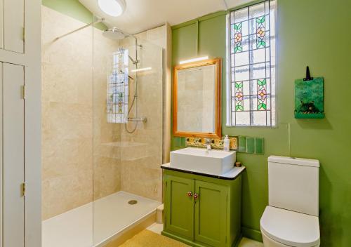 baño verde con lavabo y ducha en Owls Nest, en Stradbroke