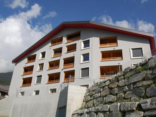 ein weißes Gebäude mit rotem Dach neben einer Steinmauer in der Unterkunft Apartment Uehlinger Rosana by Interhome in Lenzerheide