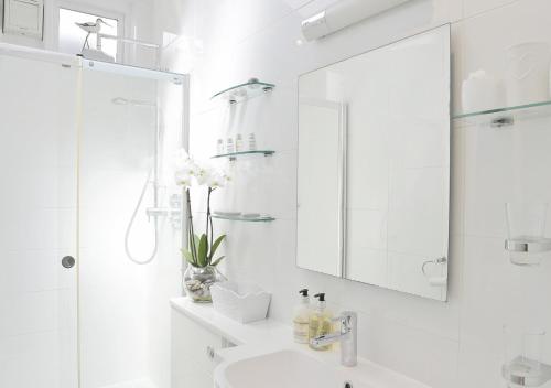 Baño blanco con lavabo y espejo en Oyster Cottage en Southwold
