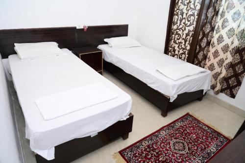 2 camas en una habitación pequeña con alfombra en Dwarka Home Stay, en Bodh Gaya