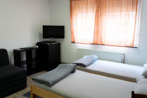 a room with two beds and a tv and a window at Apartment Eurho in Osijek